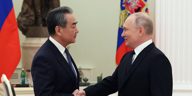 Russian President Vladimir Putin, right, shakes hands with Chinese Communist Party's foreign policy chief Wang Yi during their meeting at the Kremlin in Moscow on Feb. 22.