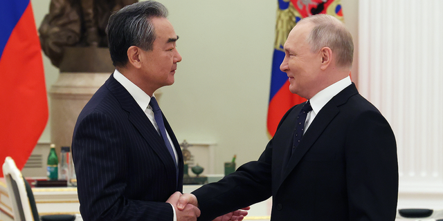 Russian President Vladimir Putin, right, shakes hands with Chinese Communist Party's foreign policy chief Wang Yi during their meeting at the Kremlin in Moscow on Feb. 22.