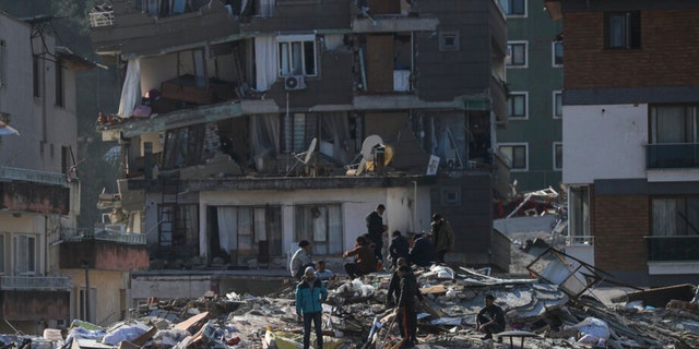 Hombres caminan entre los escombros de edificios derrumbados en Hatay, sur de Turquía, el jueves 9 de febrero de 2023. Los equipos de emergencia llevaron a cabo una serie de dramáticas operaciones de rescate en Turquía el viernes, sacando a varias personas, algunas casi ilesas, de entre los escombros, cuatro días después. después de un devastador terremoto mató a más de 20.000. 