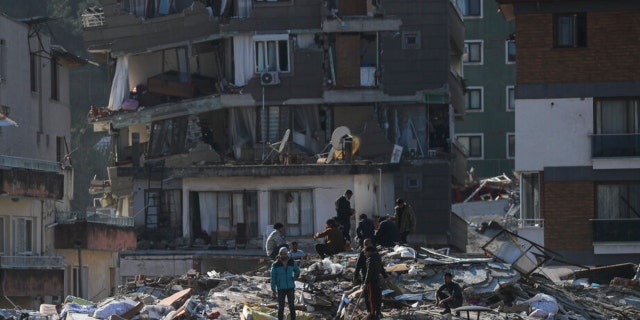 Men walk among the debris of collapsed buildings in Hatay, southern Turkey, Thursday, Feb. 9, 2023. Emergency crews made a series of dramatic rescues in Turkey on Friday, pulling several people, some almost unscathed, from the rubble, four days after a catastrophic earthquake killed more than 20,000. 