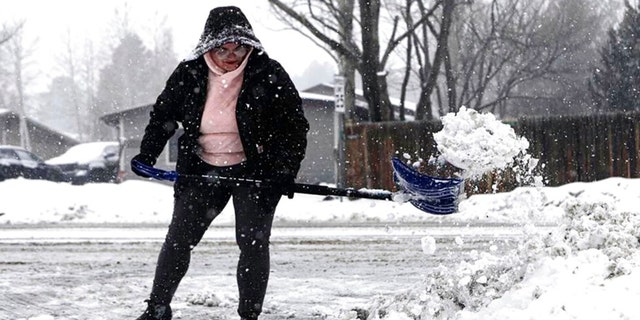 Taja Cantlon clears chunks of snow left by a snowplow from out of her driveway entrance Tuesday afternoon, Feb 14, 2023., in Flagstaff, Ariz. 