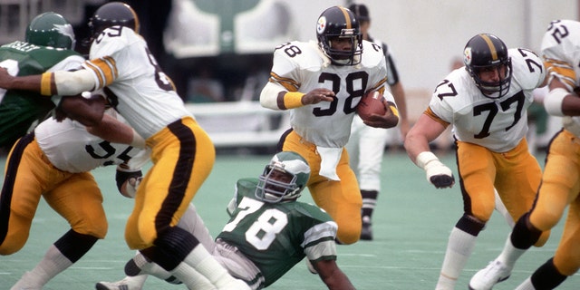 Running back Sidney Thornton, #38 of the Pittsburgh Steelers, runs with the football against defensive lineman Carl Hairston, #78 of the Philadelphia Eagles, as offensive lineman Steve Courson, #77, blocks during a preseason game at Veterans Stadium on Aug. 15, 1981 in Philadelphia.