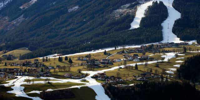People ski on a strip of snow near Schladming, Austria, on Jan. 6, 2023. Warm weather and a lack of snow wiped out nearly a month of skiing at the start of this season. 