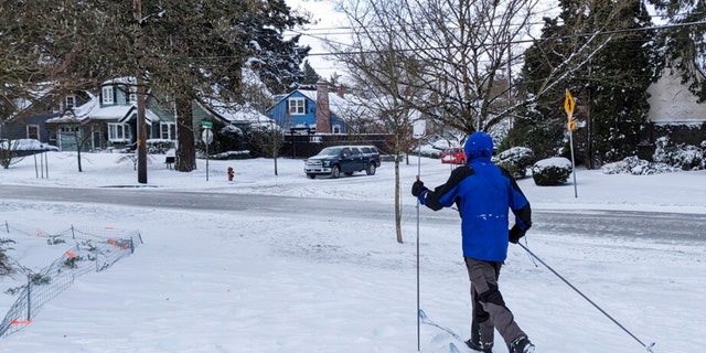 A person uses skis to get through the snow-covered Grant Park neighborhood of Portland, Oregon, Thursday Feb. 23, 2023. 