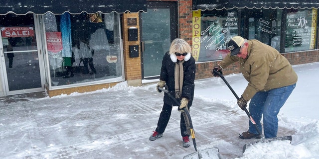 Carolyn and Dan Ellwood shovel snow outside Second Edition in Pierre, South Dakota, on Wednesday, Feb. 22, 2023. 