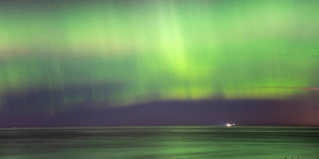 Cahaya utara (aurora borealis) menerangi langit saat pengunjung berjalan di sepanjang Pantai Hornbaek di bagian utara Sealand, Denmark, pada 27 Februari 2023.
