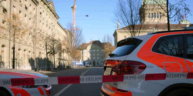 Police vehicles are parked in front of the Swiss Parliament after a man wearing a bulletproof vest was found near the entrance of the building with explosives.