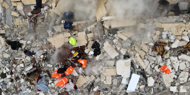 This aerial view shows residents helped by bulldozers, searching for victims and survivors in the rubble of collapsed buildings, following an earthquake in the town of Sarmada in the countryside of the northwestern Syrian Idlib province, early on Feb. 6, 2023. 