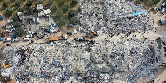 Pemandangan udara ini menunjukkan penduduk mencari korban dan penyintas di tengah puing-puing bangunan yang runtuh setelah gempa bumi di desa Besnia dekat kota Harim, di provinsi Idlib barat laut yang dikuasai pemberontak Suriah di perbatasan dengan Turki, pada 6 Februari 2022 . 