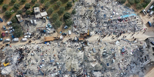 This aerial view shows residents searching for victims and survivors amidst the rubble of collapsed buildings following an earthquake in the village of Besnia near the town of Harim, in Syria's rebel-held northwestern Idlib province on the border with Turkey, on Feb. 6, 2022. 