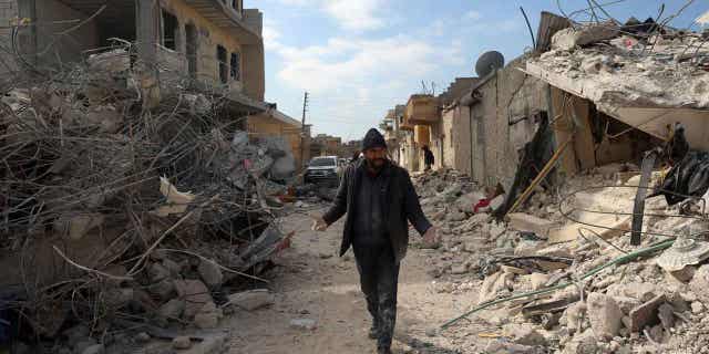 A man walks past collapsed buildings following an earthquake in the town of Jinderis, Syria, on Feb. 14, 2023. The death toll from the earthquakes that struck Turkey and northern Syria is still rising. 