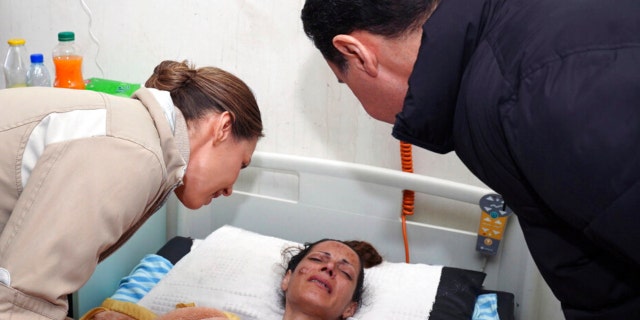 In this photo released by the official Syrian state news agency SANA, Syrian President Bashar Assad, left, and his wife Asma, visit an injured survivor of a devastating earthquake, at a hospital in the coastal city of Latakia, Syria. Saturday 12 February.  11, 2023. 