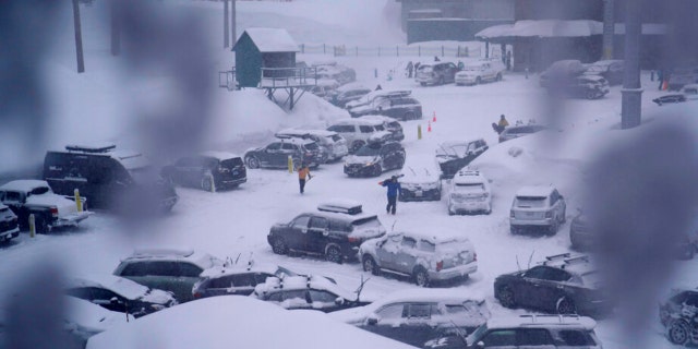 People through the parking area of the Alpine Base Area at Palisades Tahoe during a winter storm Friday, Feb. 24, 2023, in Alpine Meadows, California.