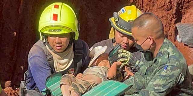 Rescuers and the military carry a child from a deep hole in Tak province, Thailand, February 7, 2023. The child fell into the hole used for groundwater pipes last night. 