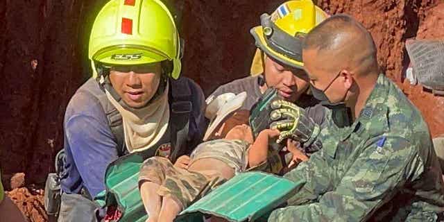 Rescue workers and military carry a child from a deep hole in the province of Tak, Thailand, on Feb. 7, 2023. The toddler fell into the hole used for groundwater pipes yesterday evening.