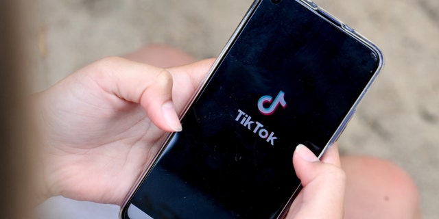 A girl holds a phone with TikTok open