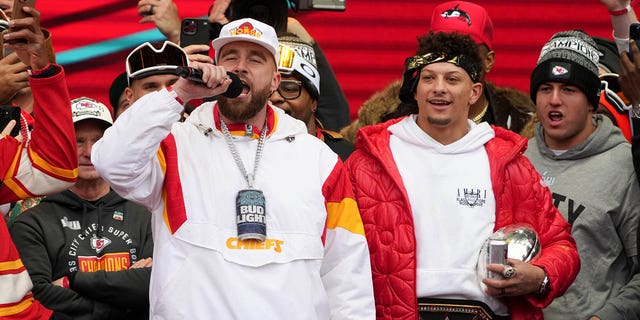 Travis Kelce, con micrófono, y Patrick Mahomes, a la derecha, de los Kansas City Chiefs celebran en el escenario durante el desfile de la victoria del Super Bowl LVII el 15 de febrero de 2023 en Kansas City, Missouri.