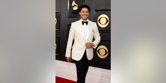 Trevor Noah rocks a white tuxedo with a black bow tie on the Grammys red carpet.