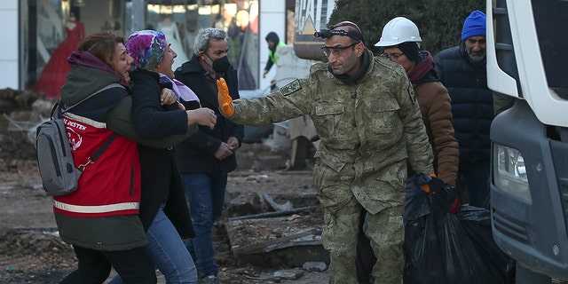 A woman reacts as rescue workers carry the body of an earthquake victim in Adiyaman, southeastern Turkey, on Thursday, Feb. 9, 2023.