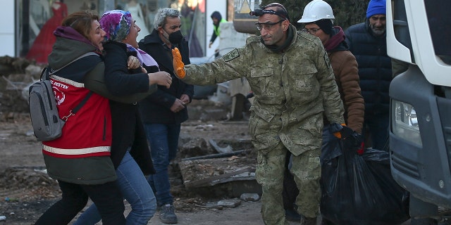 A woman reacts as rescue workers carry the body of an earthquake victim in Adiyaman, southeastern Turkey, Thursday, Feb. 9, 2023.