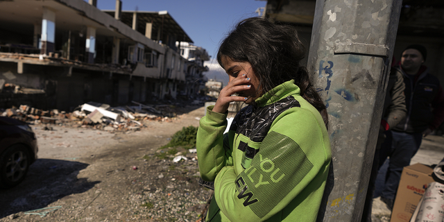 A girl stands next to destroyed buildings in Antakya, southern Turkey, on Wednesday, Feb. 8.
