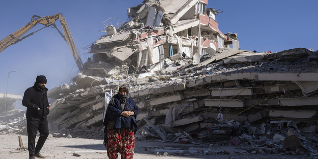 Local residents walk in front of a destroyed building in Nurdagi, southeastern Turkey, on Thursday, Feb. 9.