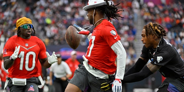 AFC wide receiver Davante Adams of the Las Vegas Raiders, center, pitches the ball to AFC wide receiver Tyreek Hill (10) of the Miami Dolphins as NFC cornerback Jalen Ramsey of the Los Angles Rams defends during the flag football event at the Pro Bowl Games, Feb. 5, 2023, in Las Vegas.