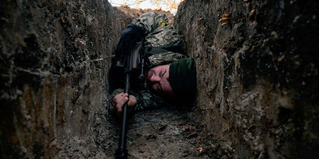 A Ukrainian soldier hides from a helicopter airstrike amid Russia's invasion of Ukraine, near Demydiv, Ukraine March 10, 2022. 