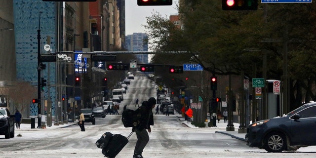 Pedestrians walk across icy roads as a cold weather front moves through Dallas, Texas, on Jan. 31, 2023.