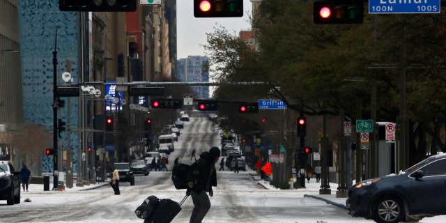 Pedestrians walk across icy roads as a cold weather front moves through Dallas, Texas, U.S., January 31, 2023.