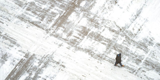 A man crosses a snow covered S. Sixth St. Wednesday, Feb. 22, 2023, in downtown Minneapolis. 