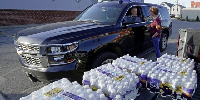 Becky Rance, center, talks with a police officer as she hands out water from the back of her truck in downtown East Palestine, Ohio, as the cleanup of portions of a Norfolk Southern freight train that derailed over a week ago continues, Wednesday. 