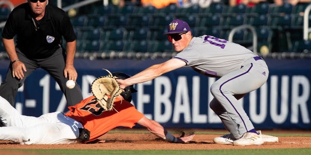 Jacob Melton dari Oregon State Beavers (29) meraih base pertama saat infielder Washington Huskies Will Simpson (10) gagal melakukan lemparan selama turnamen bisbol PAC-12 25 Mei 2022, di Stadion Scottsdale di Scottsdale, Ariz.