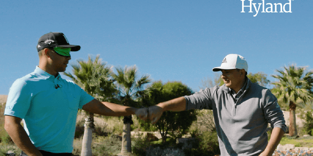 Xander Schauffele fists-bumps his coach after completing one of the challenges.
