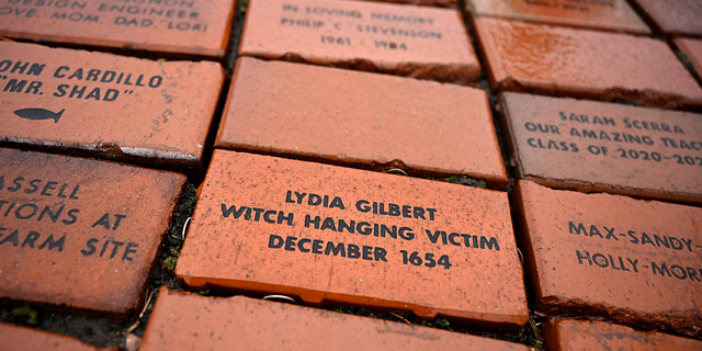 In this Tuesday, Jan. 24, 2023 photo, a brick memorializing Lydia Gilbert is placed in a town Heritage Bricks installation in Windsor, Conn. In 1651, an accident during a local militiamen training exercise led to the accusation of witchcraft and hanging of Lydia Gilbert.