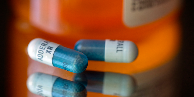 Adderall XR capsules are displayed in front of a medicine bottle.