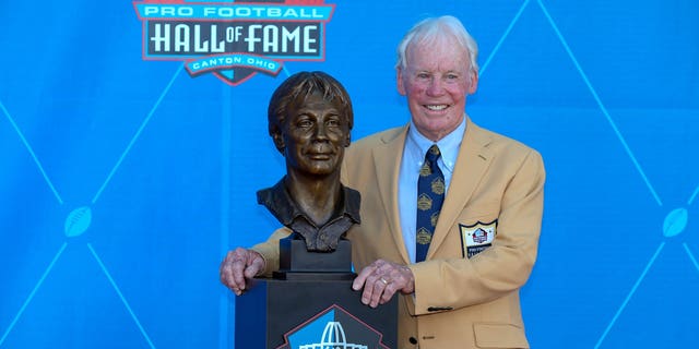 Bobby Beesard poses for photographers next to the Hall of Fame bust after it was enshrined on August 4, 2018.