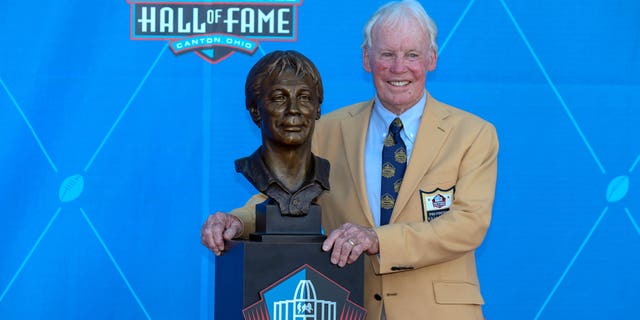 Bobby Beathard posa para los fotógrafos junto a su busto del Salón de la Fama después de su exaltación el 4 de agosto de 2018.