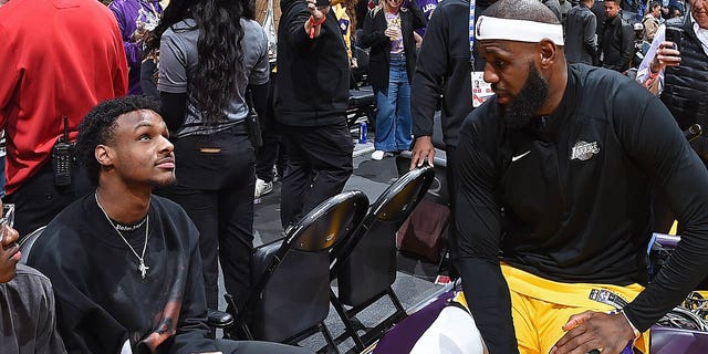 Bronny James and his father, LeBron James of the Los Angeles Lakers, talk during a game at Crypto.Com Arena in Los Angeles on Feb. 7, 2023.