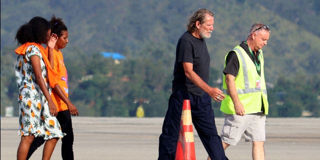 Bryce Barker, second to the right, who was held hostage for a week in Papua New Guinea by an armed group, is being escorted from a plane following his release on Feb. 26, 2023. 