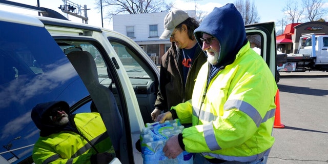Volunteer Larry Culler helps load water into a car in East Palestine, Ohio, as cleanup from the Feb. 3 Norfolk Southern train derailment continues, Friday, Feb. 24, 2023. 