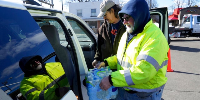 Volunteer Larry Culler helps load water into a car in East Palestine, Ohio, as cleanup from the Feb. 3 Norfolk Southern train derailment continues, Friday, Feb. 24, 2023. 