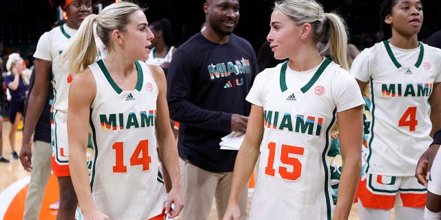 Haley Cavinder (14) y Hanna Cavinder (15) de los Miami Hurricanes hablan en el campo después de derrotar a los Clemson Tigers en el Watsco Center el 16 de febrero de 2023 en Coral Gables, Florida.