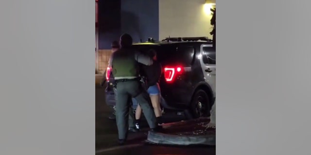 LASD deputy detains a woman at the scene of a catalytic converter theft incident-turned homicide on Feb. 11 in Palmdale, California.