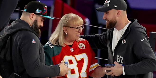 Mother Donna Kelce (C) gives cookies to Jason Kelce (L) #62 of the Philadelphia Eagles and Travis Kelce (R) #87 of the Kansas City Chiefs from her son during opening night of Super Bowl LVII presented by Fast Twitch at the Footprint Center on February 06, 2023, in Phoenix, Arizona.
