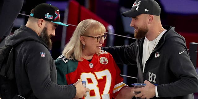 Mother Donna Kelce (C) gives cookies to her son's Jason Kelce (L), #62 of the Philadelphia Eagles ,and Travis Kelce (R), #87 of the Kansas City Chiefs, during Super Bowl LVII Opening Night presented by Fast Twitch at Footprint Center on February 6, 2023 in Phoenix, Arizona.