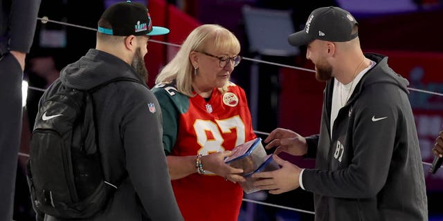 Mother Donna Kelce (C) gives cookies to Jason Kelce (L) #62 of the Philadelphia Eagles and Travis Kelce (R) #87 of the Kansas City Chiefs from her son during opening night of Super Bowl LVII presented by Fast Twitch at the Footprint Center on February 06, 2023, in Phoenix, Arizona.