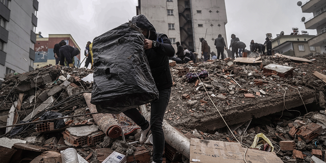 People and emergency crews search through the rubble at a destroyed building in Gaziantep, Turkey on Monday, February 6, 2023.