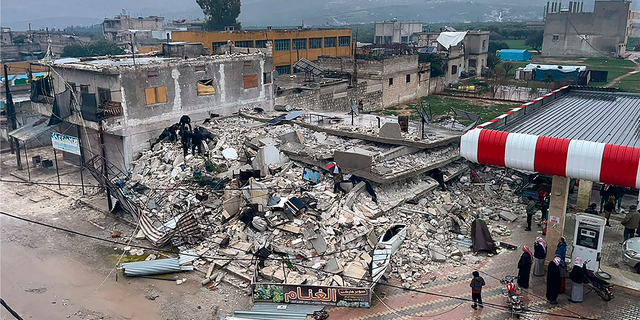 People search through the wreckage of a collapsed building in Azmarin town, in Idlib province, northern Syria.