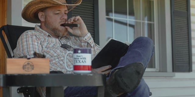 Gabriel Rench smokes cigar on front porch